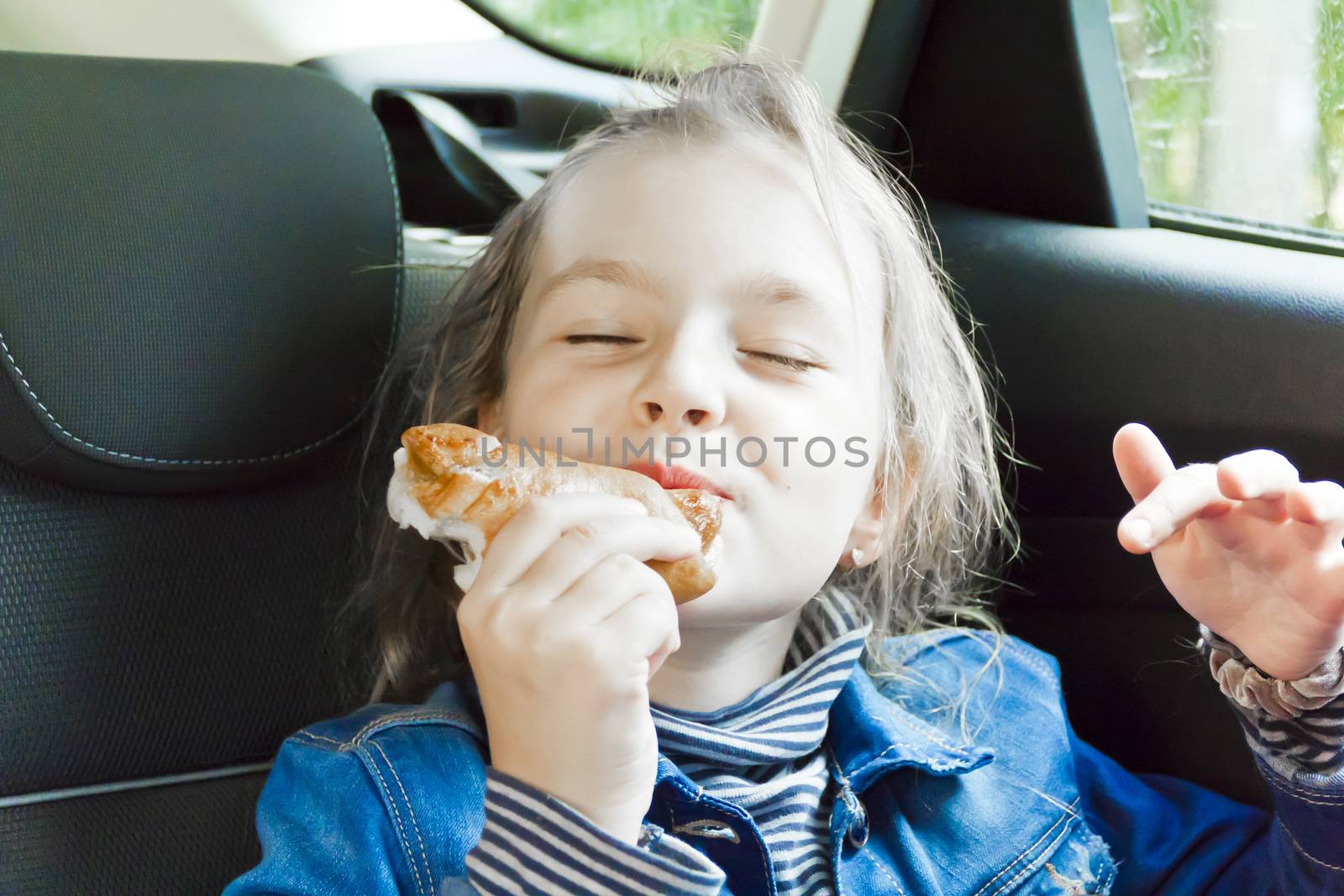 Eating cute girl with blond wet hair sitting inside car