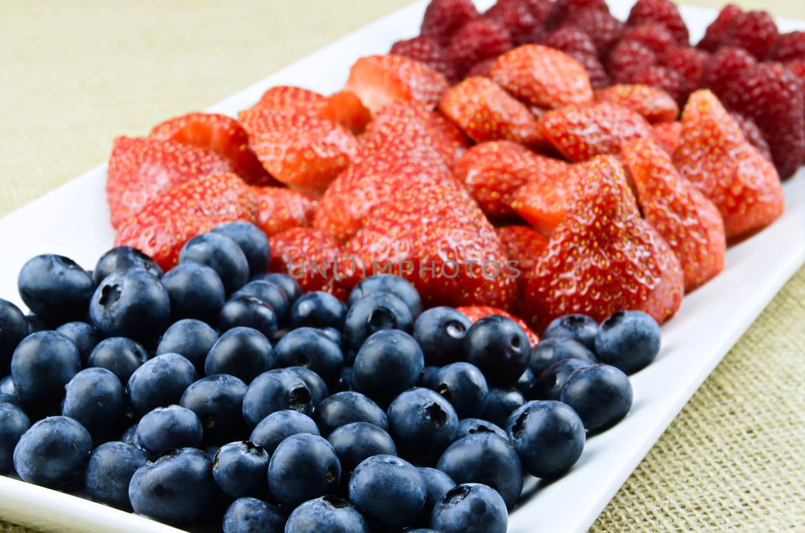 Strawberry, raspberry, blueberry fruits on white plate
