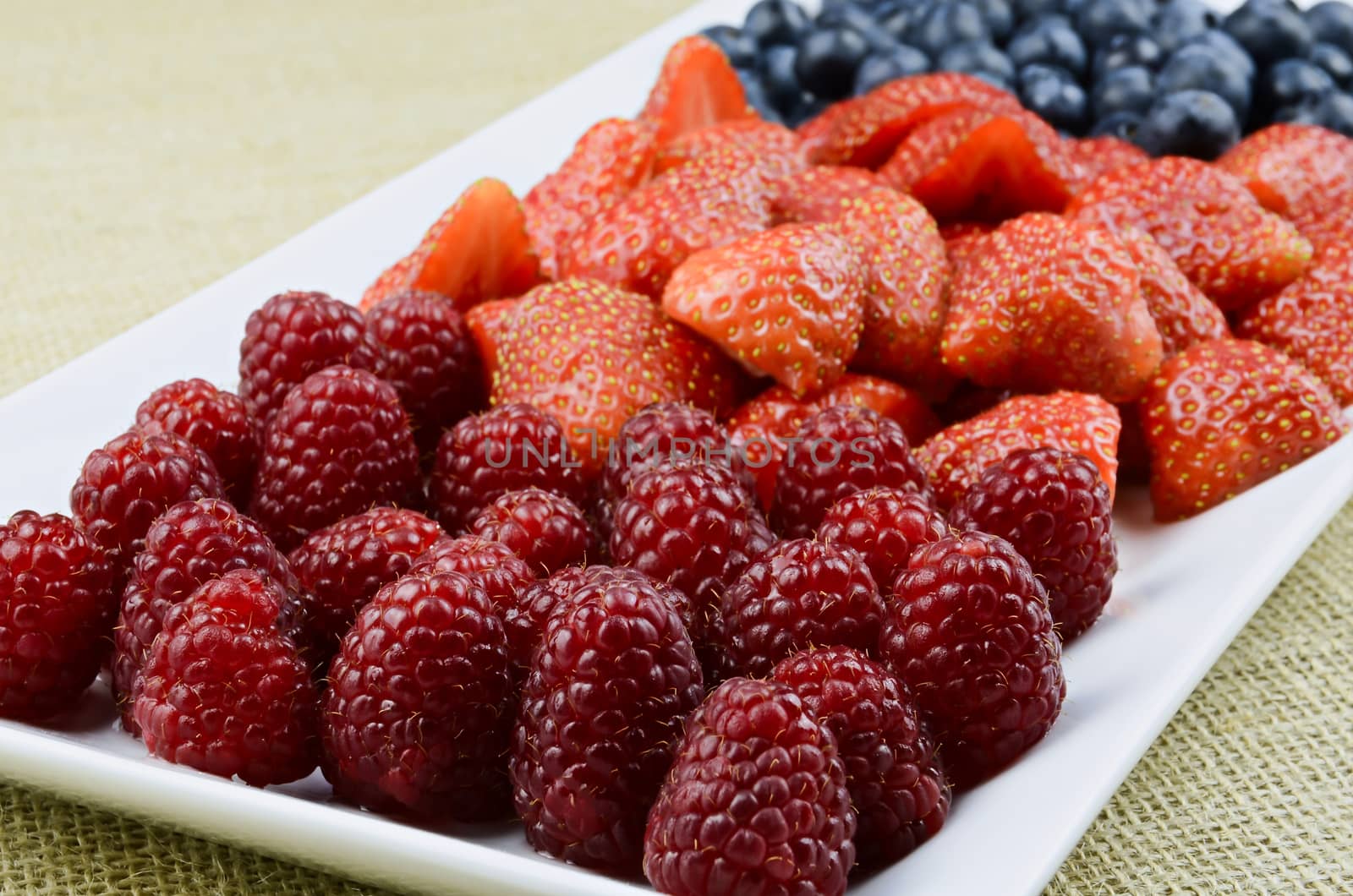 Strawberry, raspberry, blueberry fruits on white plate
