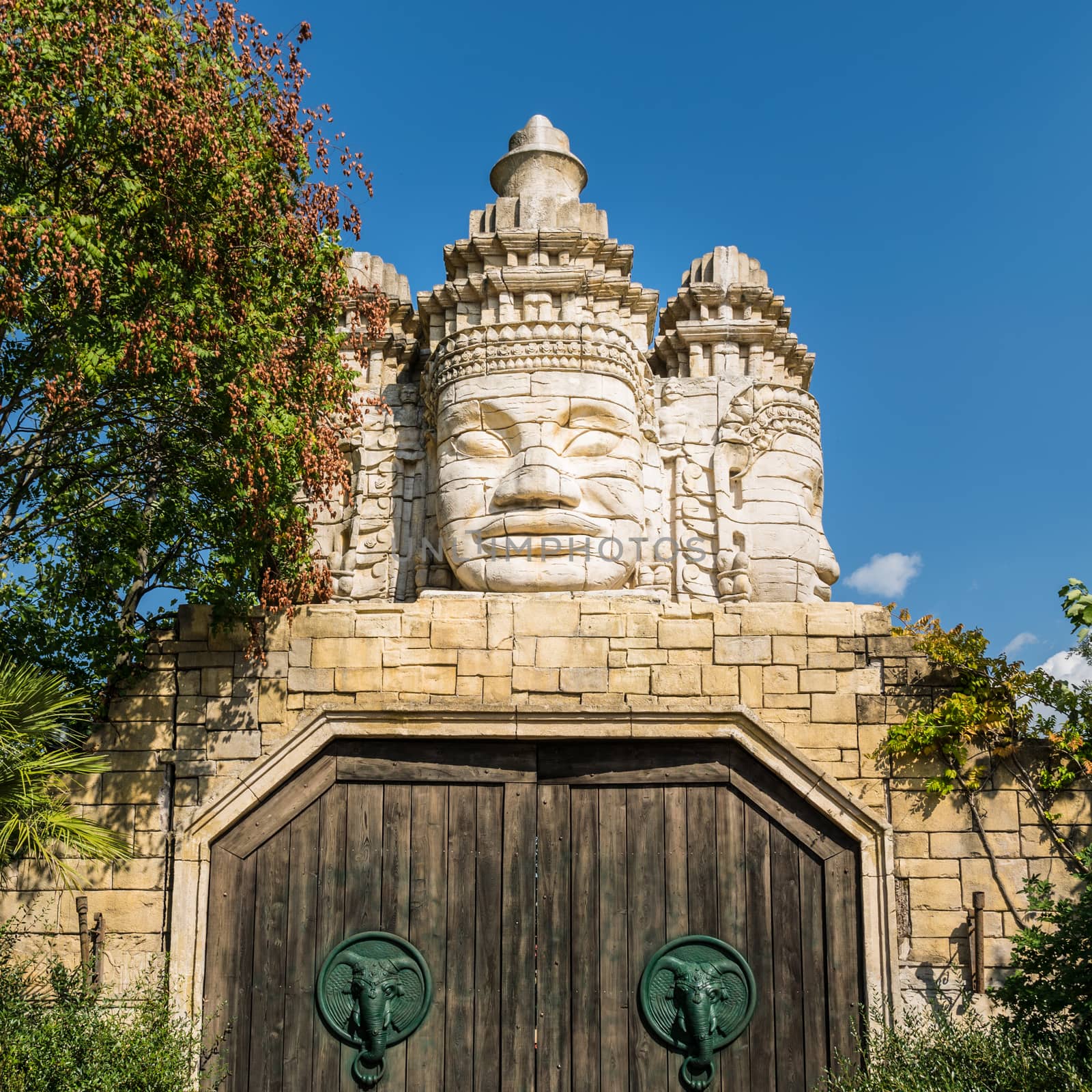 Stone faces of a temple and wooden portal with door knocker shaped like elephant's head.