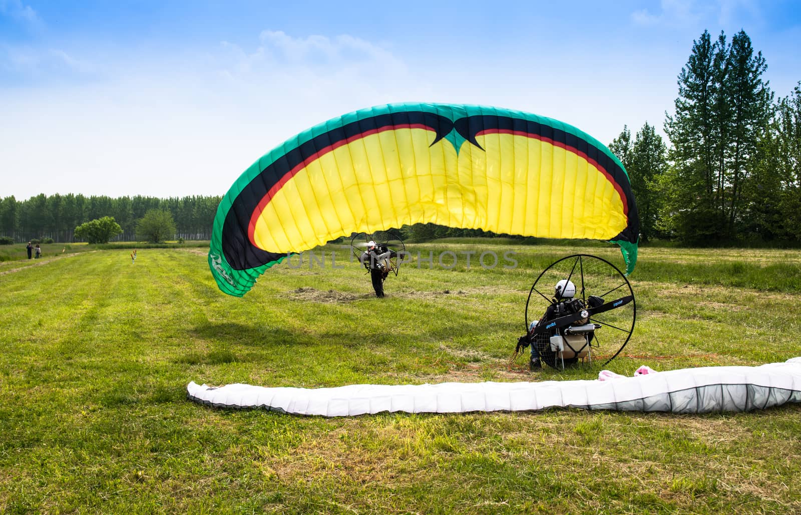 man with motorized paraglider takes off from a field by Isaac74