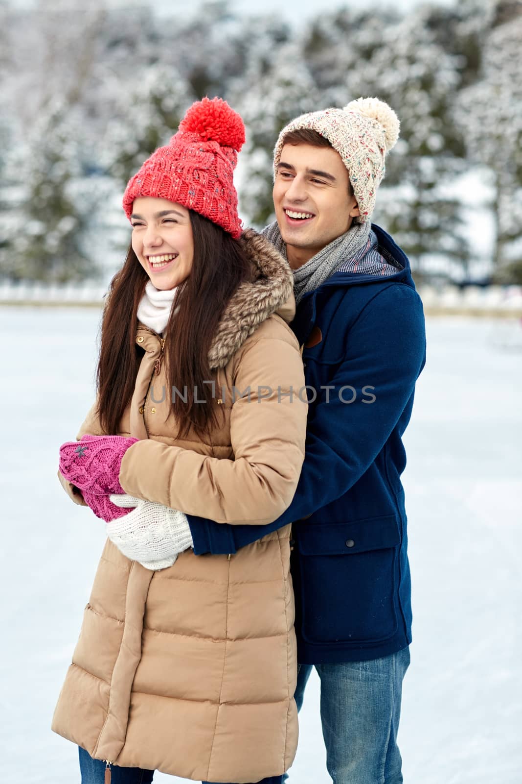 people, winter, love and leisure concept - happy couple hugging ice skating on rink outdoors