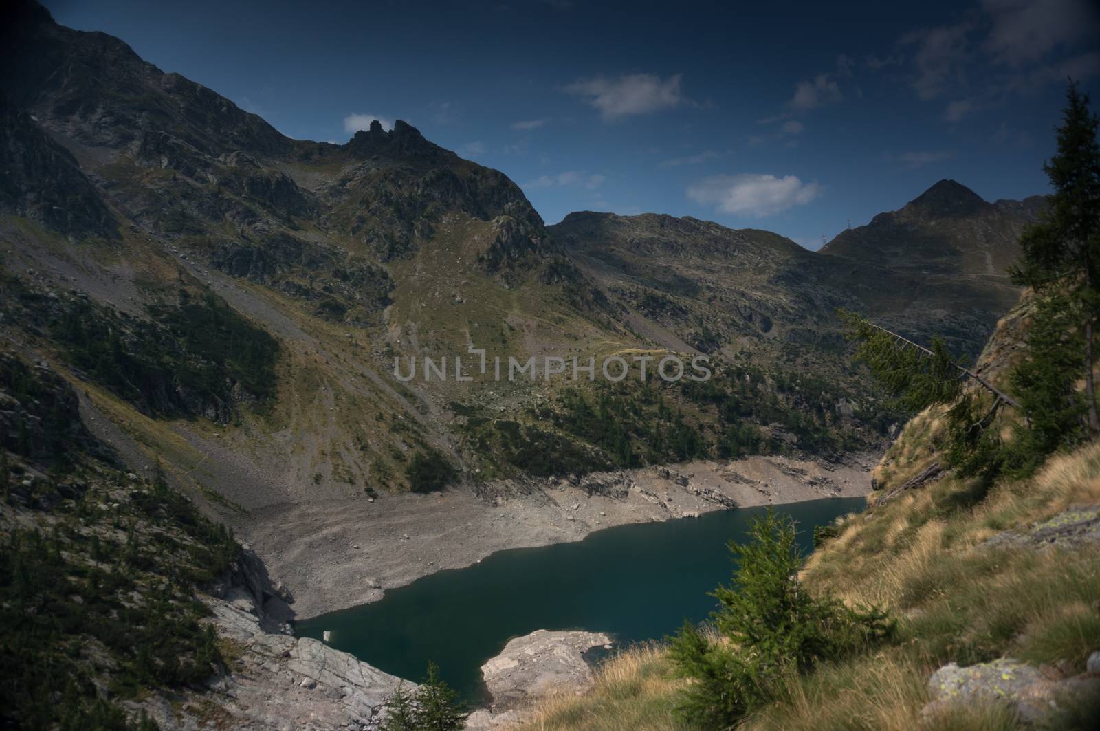 Hiking in summer Alps to blue lake of mountain