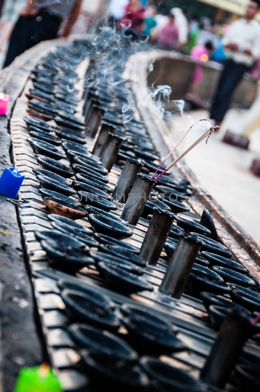 Incense sticks, candles and small bowls in front of shwedagon pagoda