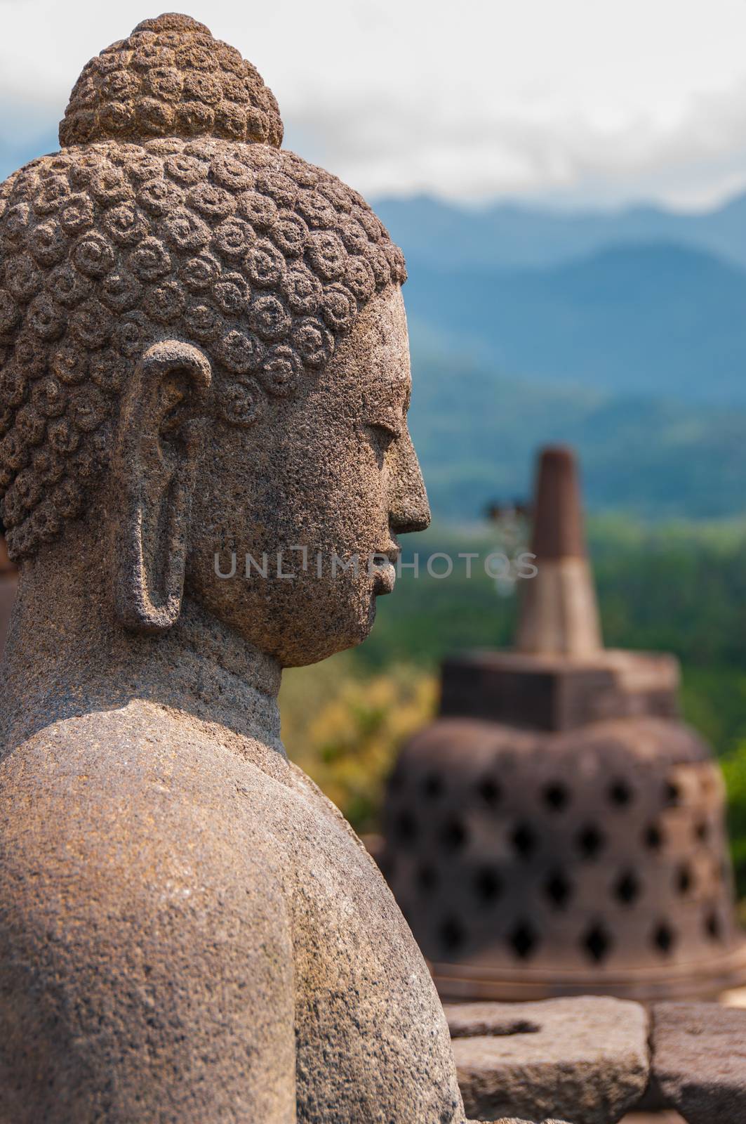 Sitting stone Buddha in front of Stupa at borobudur near Yogyakarta in Indonesia. Borobudur is the biggest buddhist temple in the world.