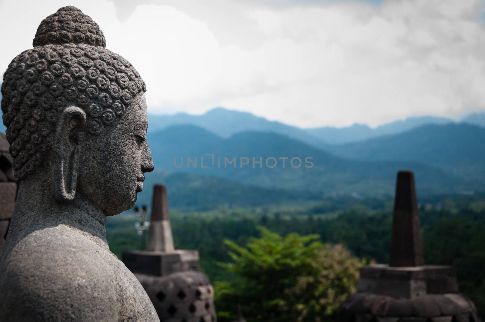 Stone budhha sideview in front of two stupas at Borobudur near Yogyakarta in Indonesia.