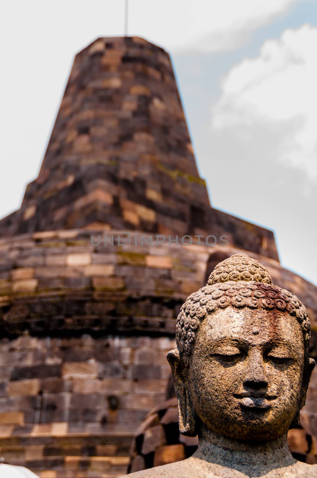 Buddha stone sculpure sitting in front of stupa at Borobudur, near Yogyakarta, Indonesia.