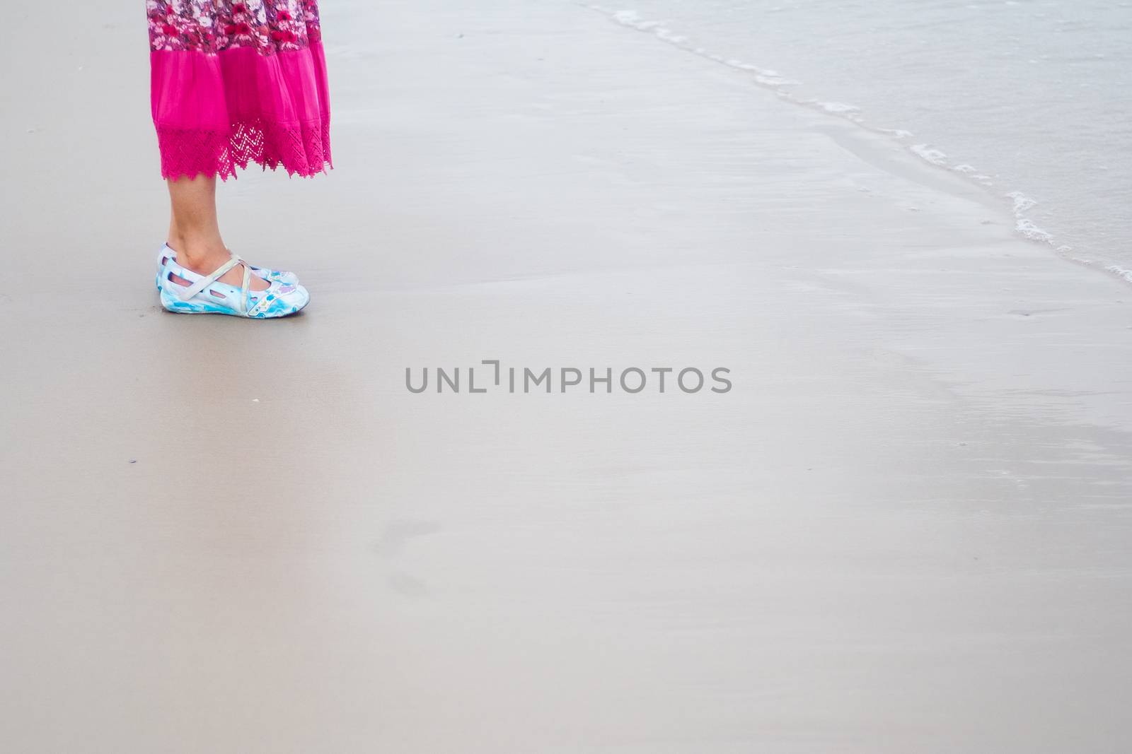 asian woman with pink long skirt and blue shoes standing by the sand beach