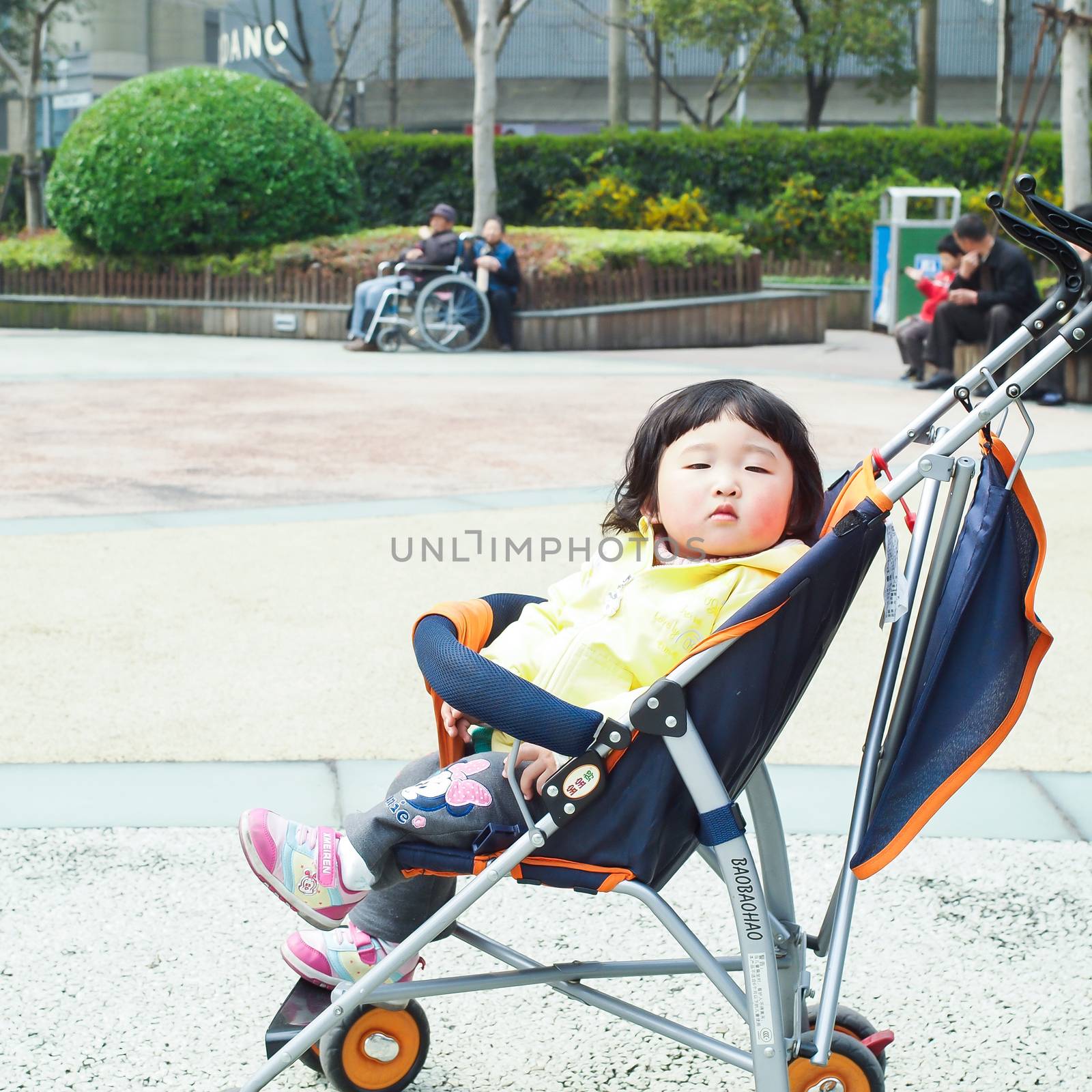 SHIANGHAI, CHINA - April 8, 2011 :  Chinese cute girl kid with baby carriage in the park