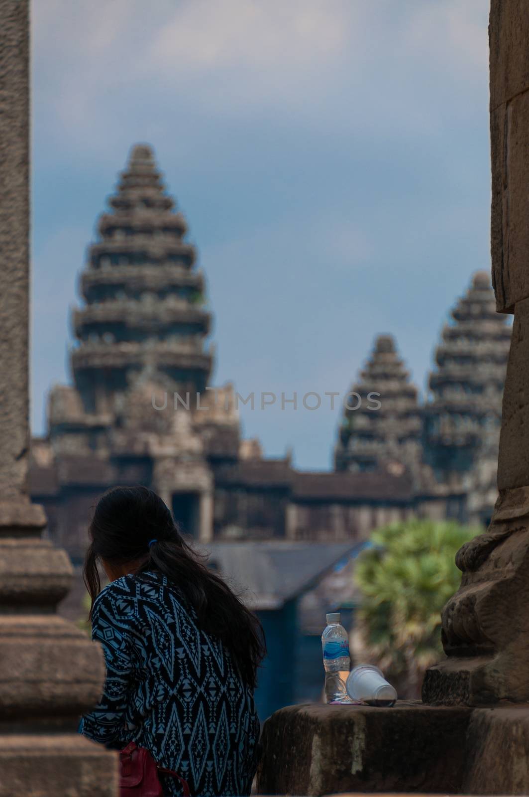 Girl from behind sitting in front of Angkor Wat in the morning