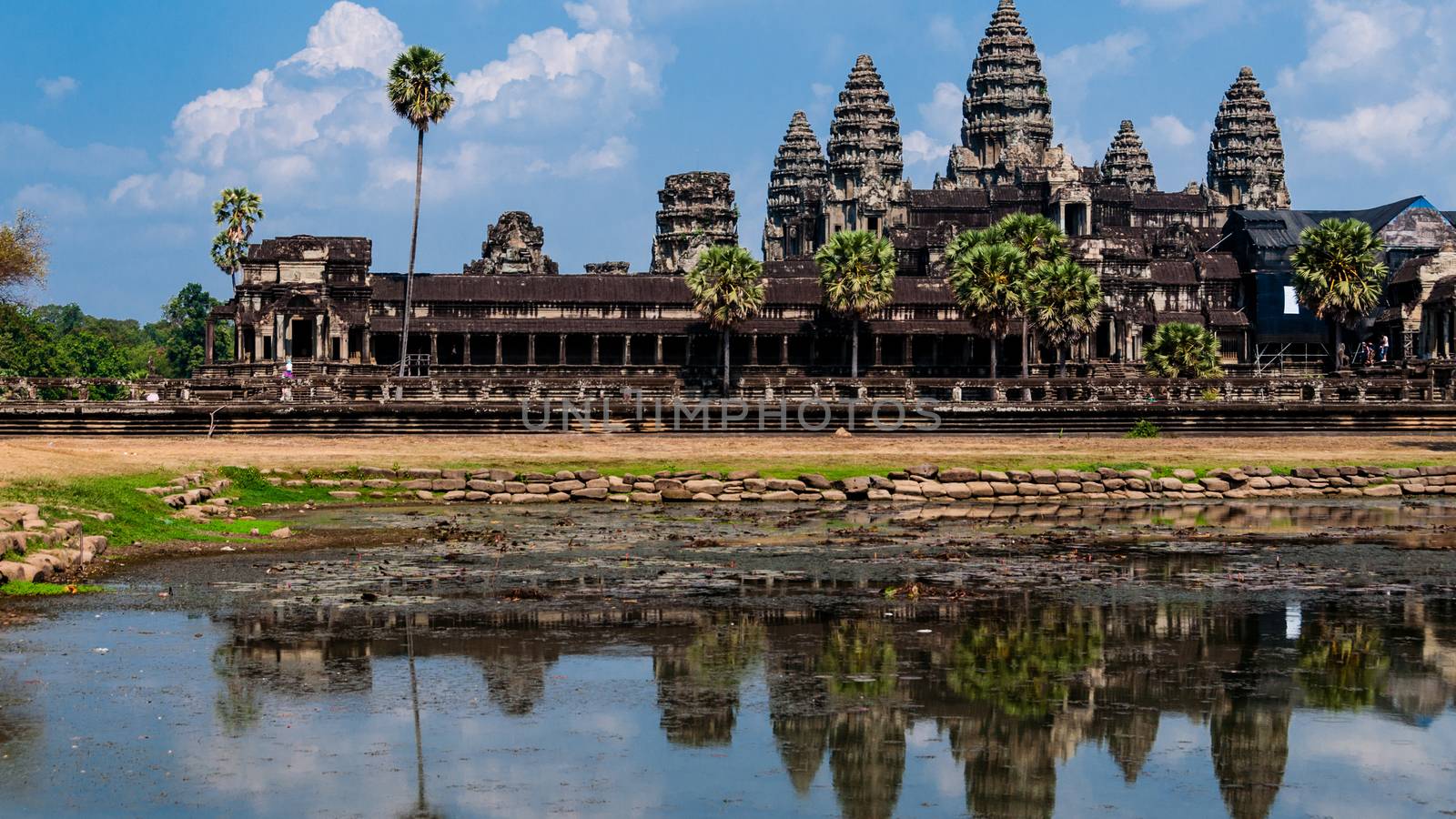 Front of Angkor Wat with reflection in water and a blue sky above