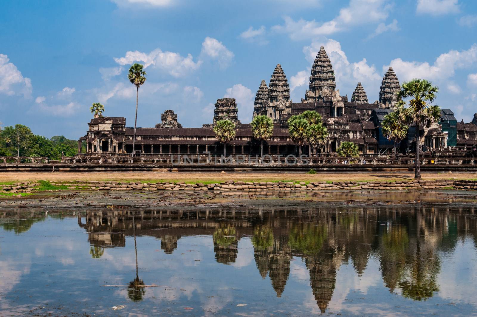 Front of Angkor Wat with reflection in water and a blue sky above