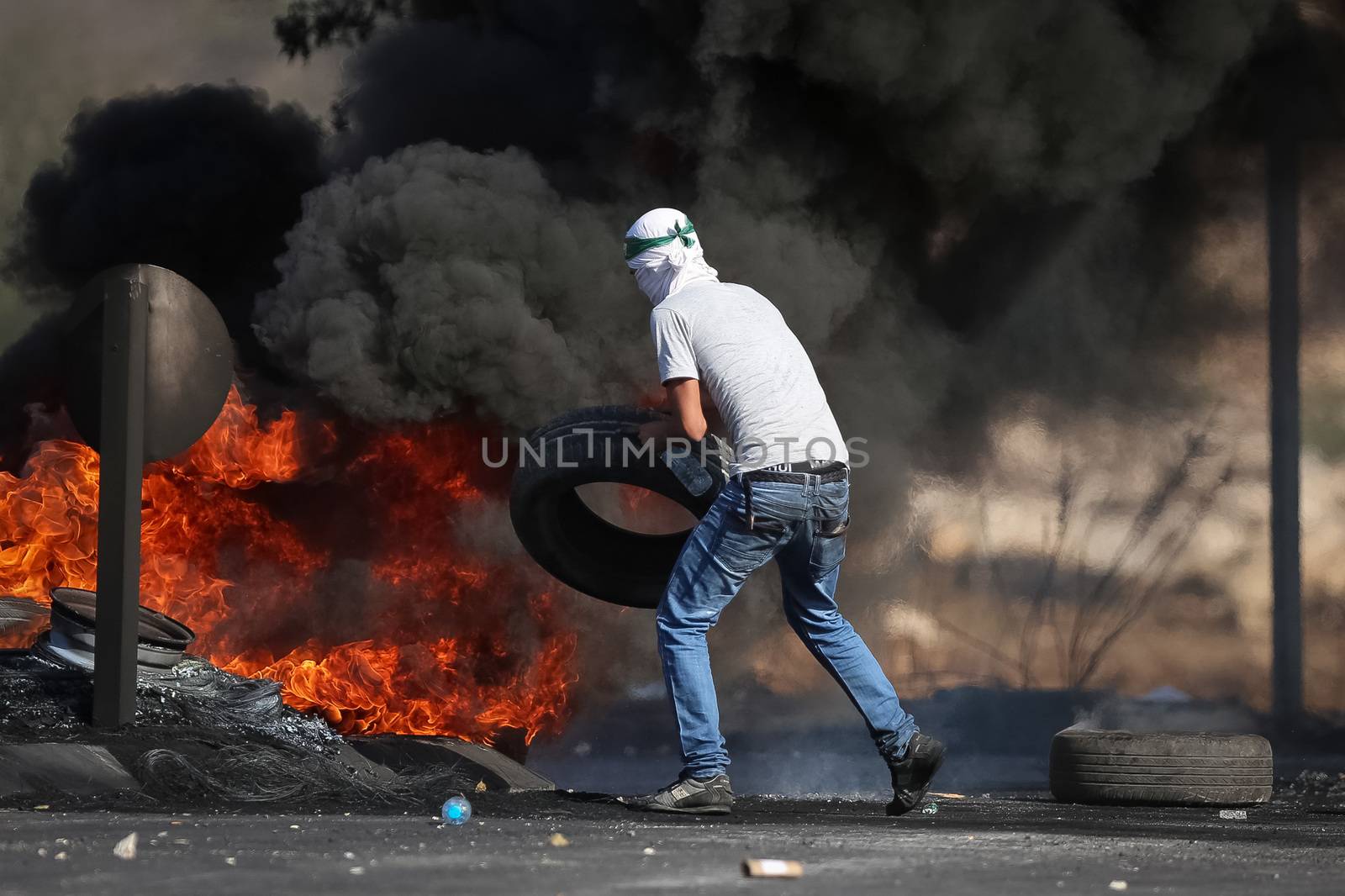 WEST BANK, Ramallah: A young masked Palestinian burns a tire in a street of northern Ramallah, West Bank, on October 17, 2015, during clashes with Israeli army near Beit El Israeli settlement.