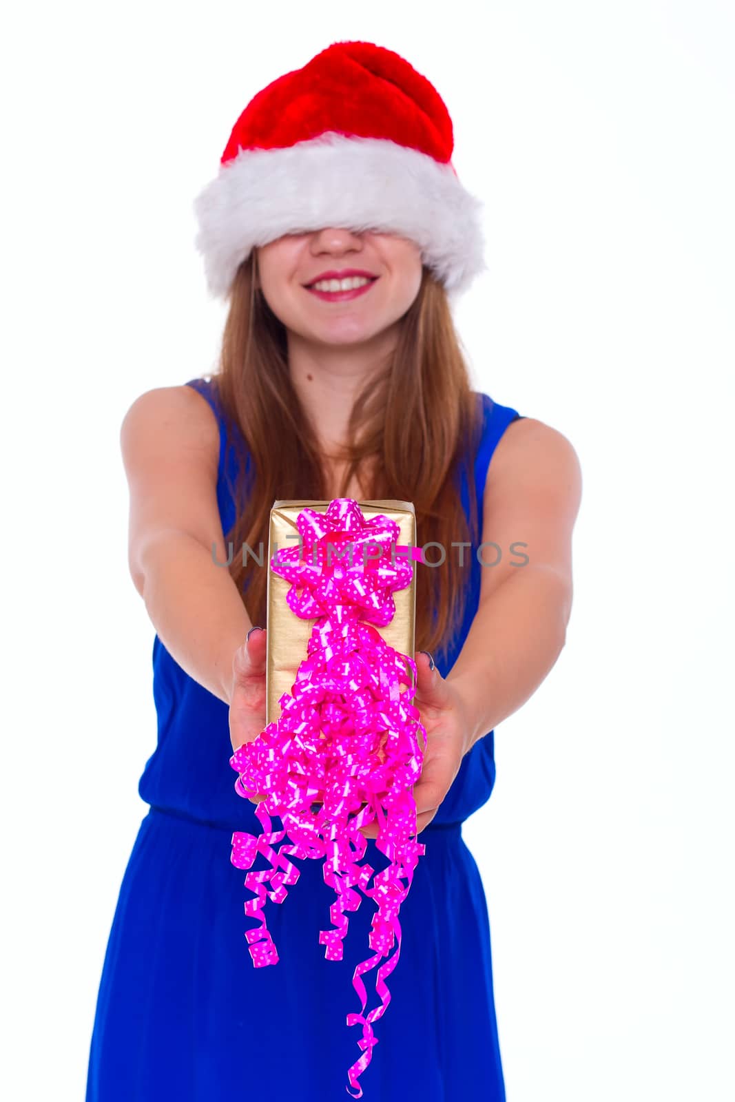 Young happy girl in Christmas hat. Standing indoors and holding huge christmas gift. isolate