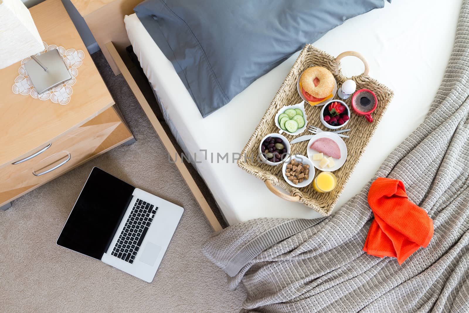 Laptop on Floor Beside Bed with Breakfast Tray by coskun