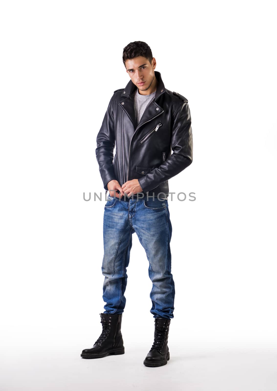 Handsome young man wearing leather jacket, t-shirt and jeans, on white background looking at camera