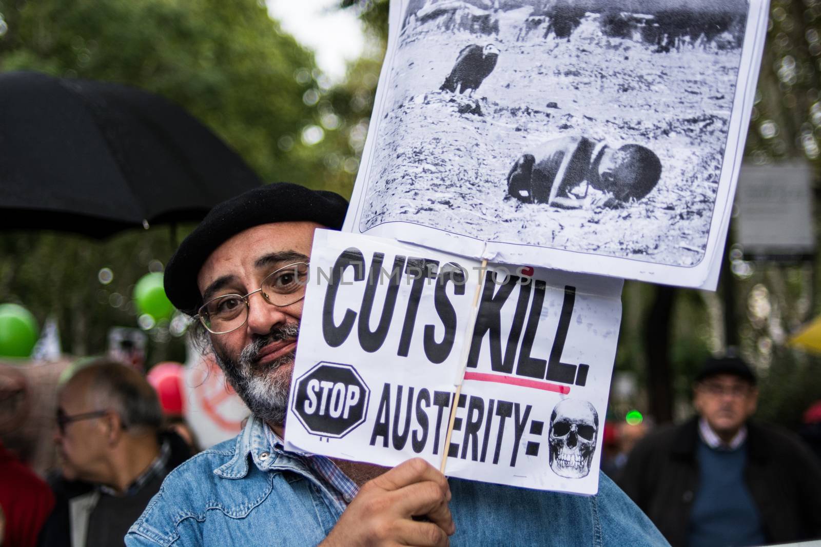 SPAIN, Madrid: A man with an anti-austerity poster attends a protest against the Transatlantic Trade and Investment Partnership in Madrid, Spain on October 17, 2015. Leaders are still reaching an agreement on the TTIP, a deal designed to boost the US economy and European Union by removing tariffs and other barriers to trade and foreign investment. Protesters argue the TTIP will support corporations at the expense of citizens, increase poverty and inequality and harm the environment. 