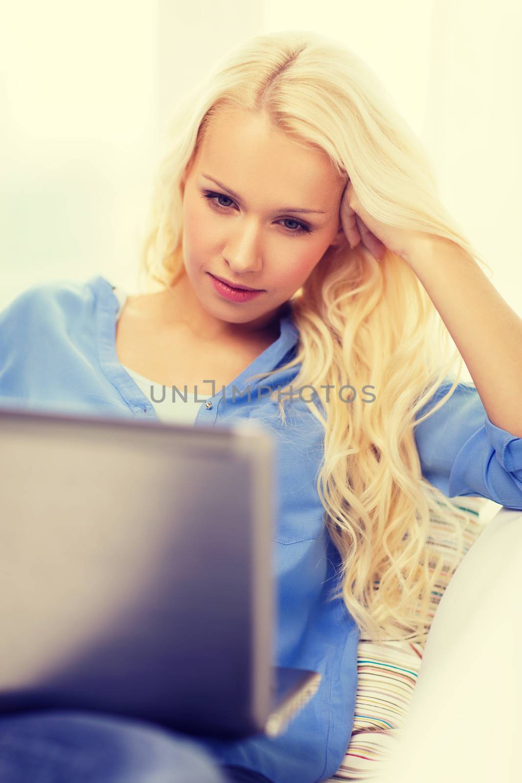 home, technology and internet concept - woman sitting on the couch with laptop computer at home