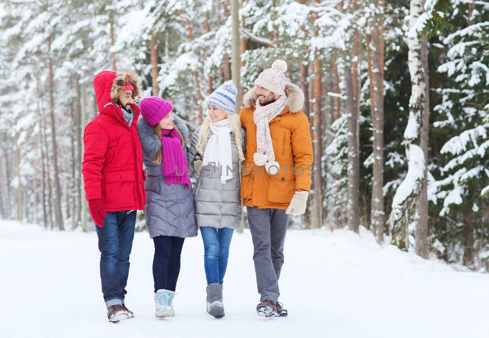 love, relationship, season, friendship and people concept - group of smiling men and women walking and talking in winter forest