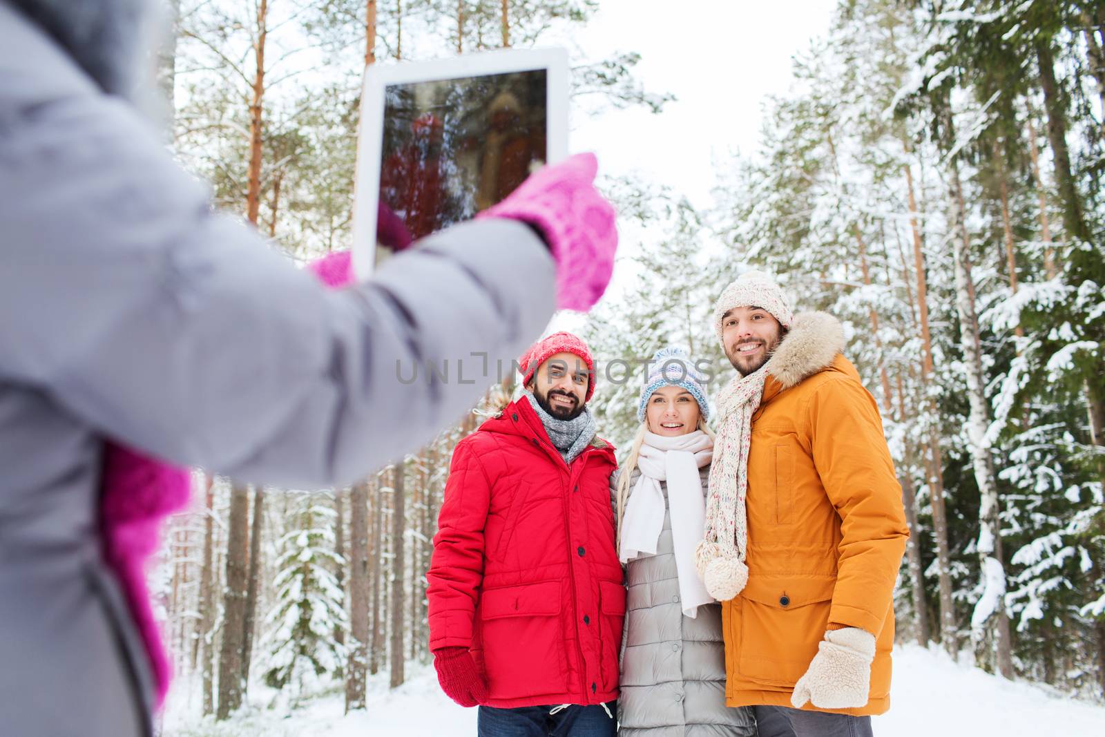 smiling friends with tablet pc in winter forest by dolgachov
