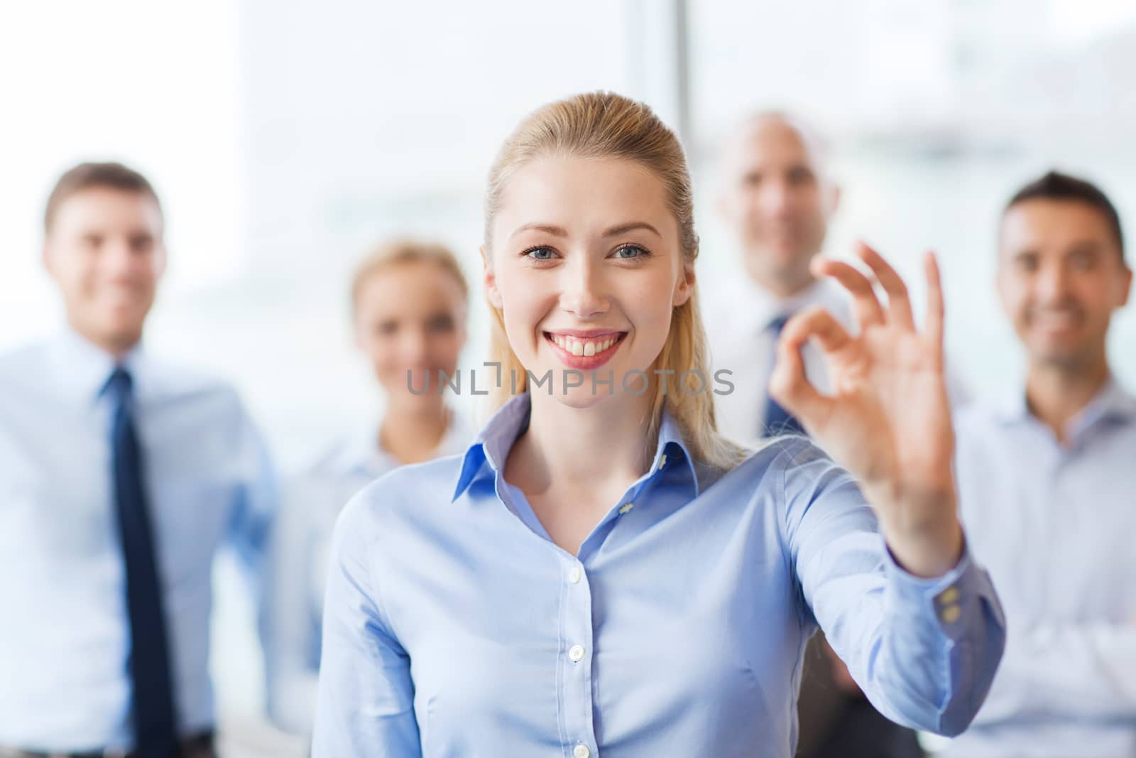 smiling businesswoman showing ok sign in office by dolgachov