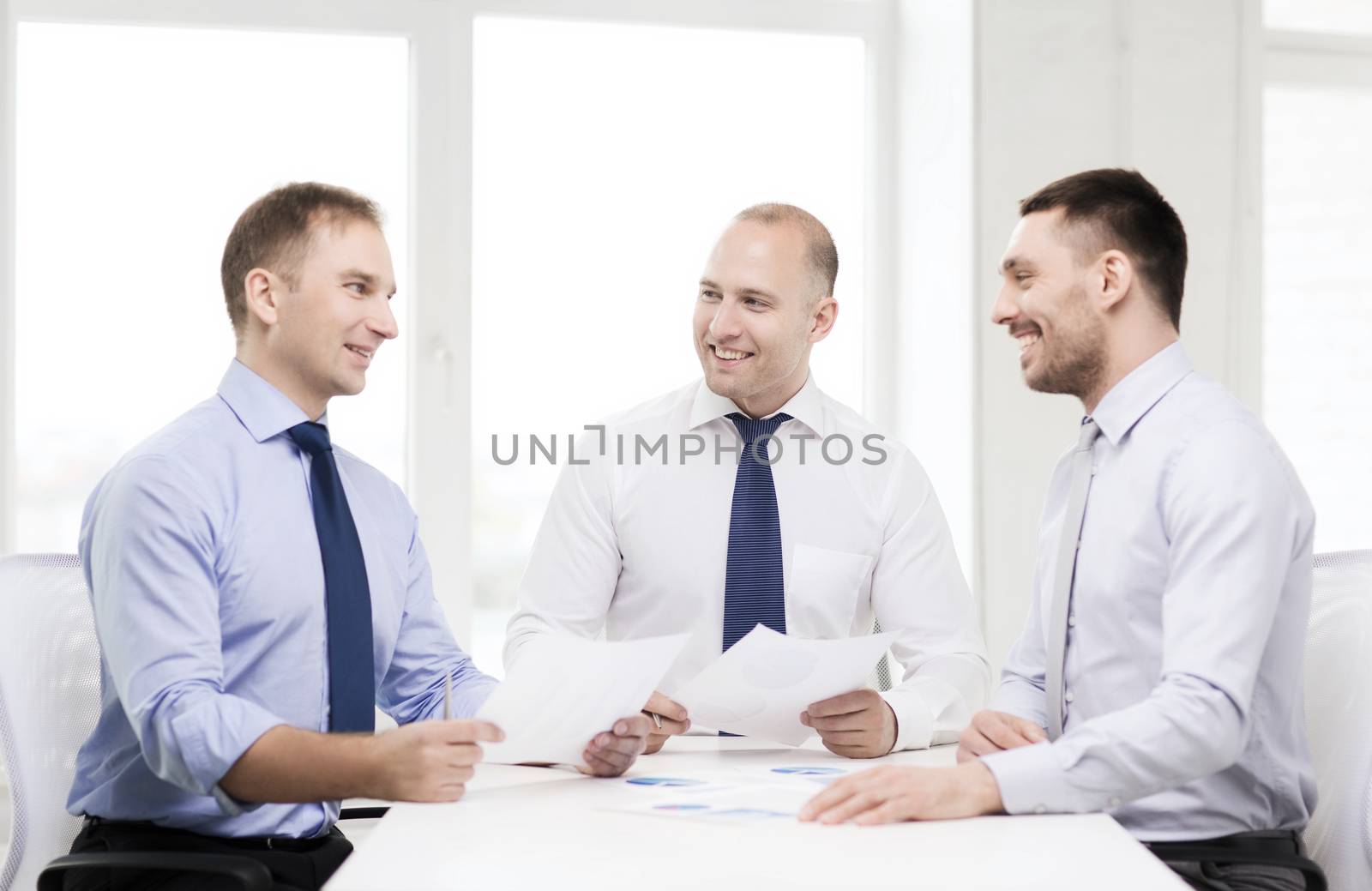 smiling businessmen with papers in office by dolgachov