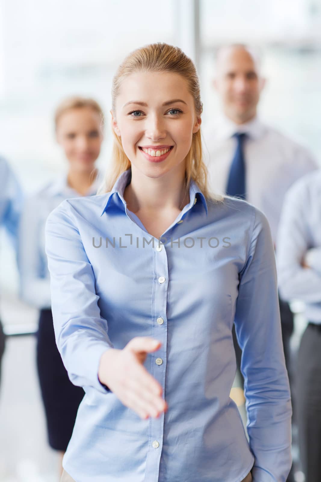 smiling businesswoman making handshake in office by dolgachov