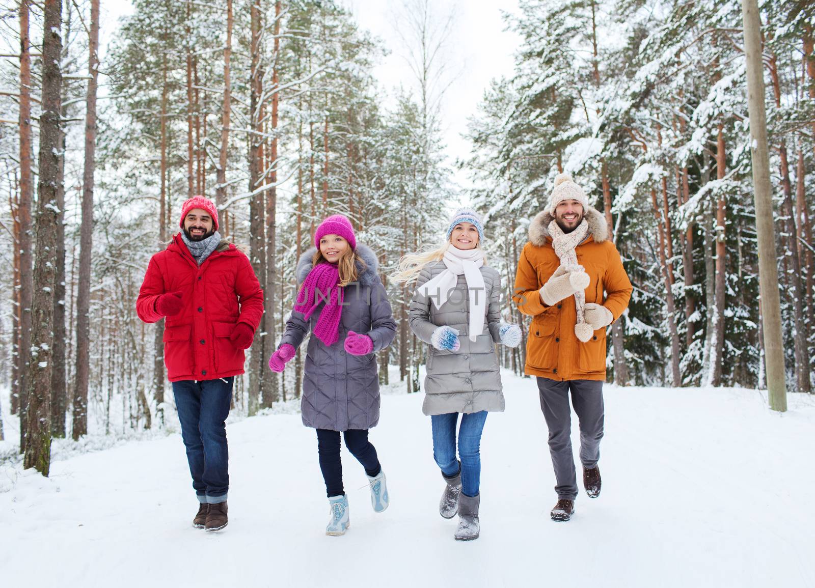 love, relationship, season, friendship and people concept - group of smiling men and women running in winter forest