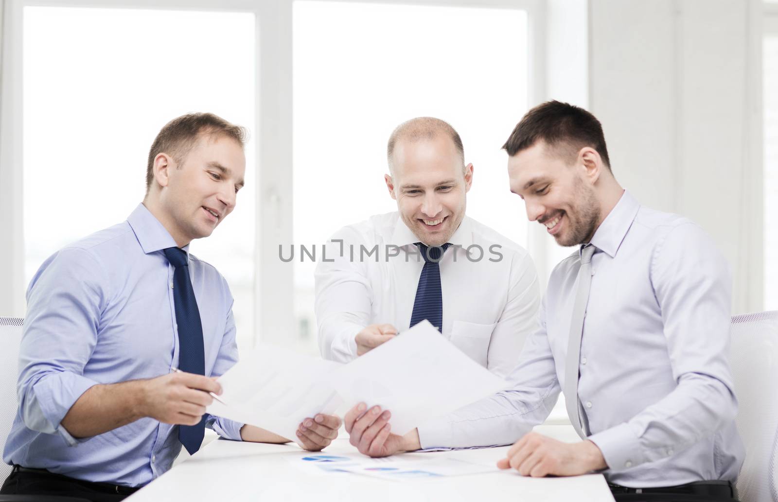 smiling businessmen with papers in office by dolgachov