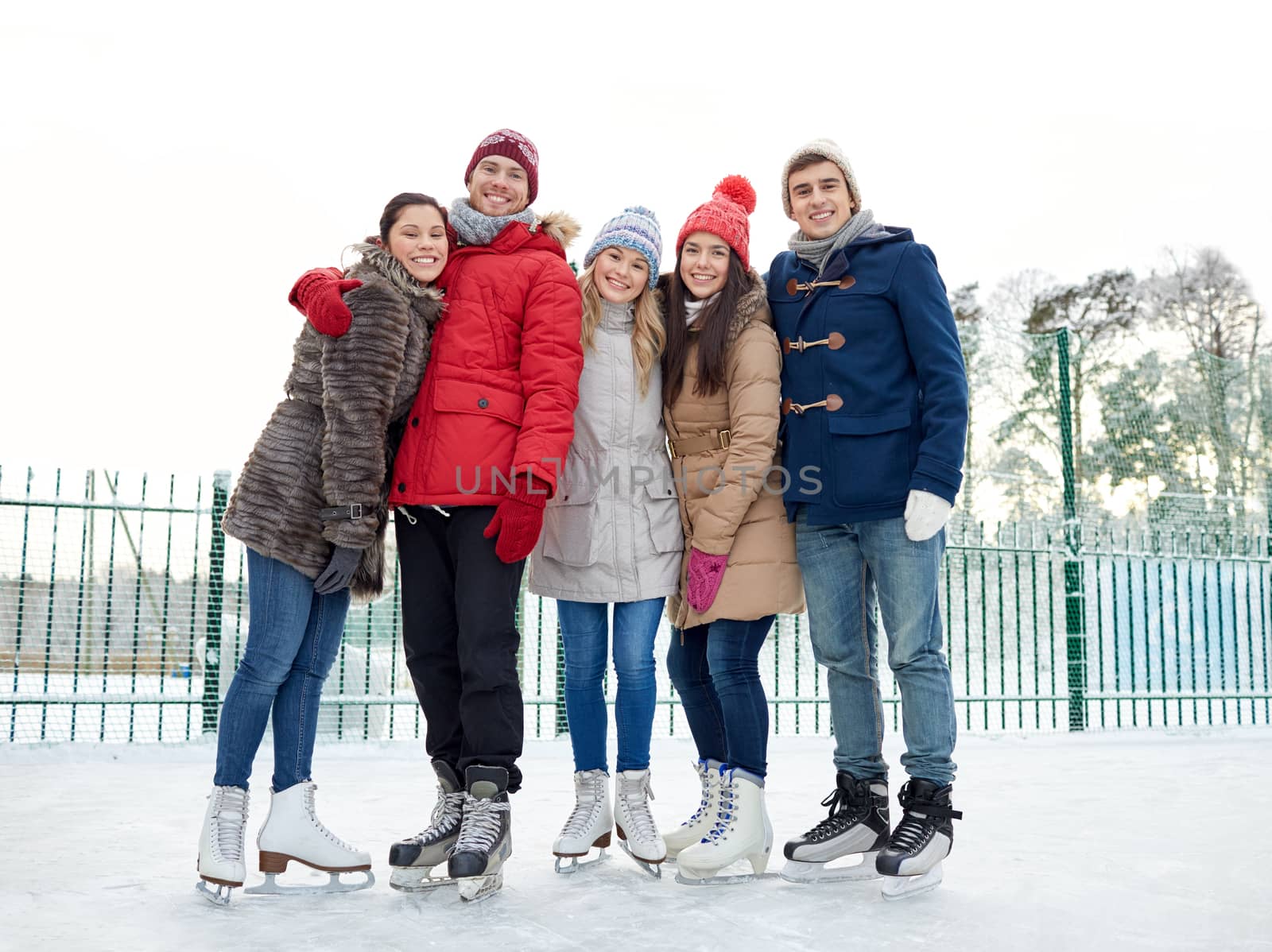 happy friends ice skating on rink outdoors by dolgachov