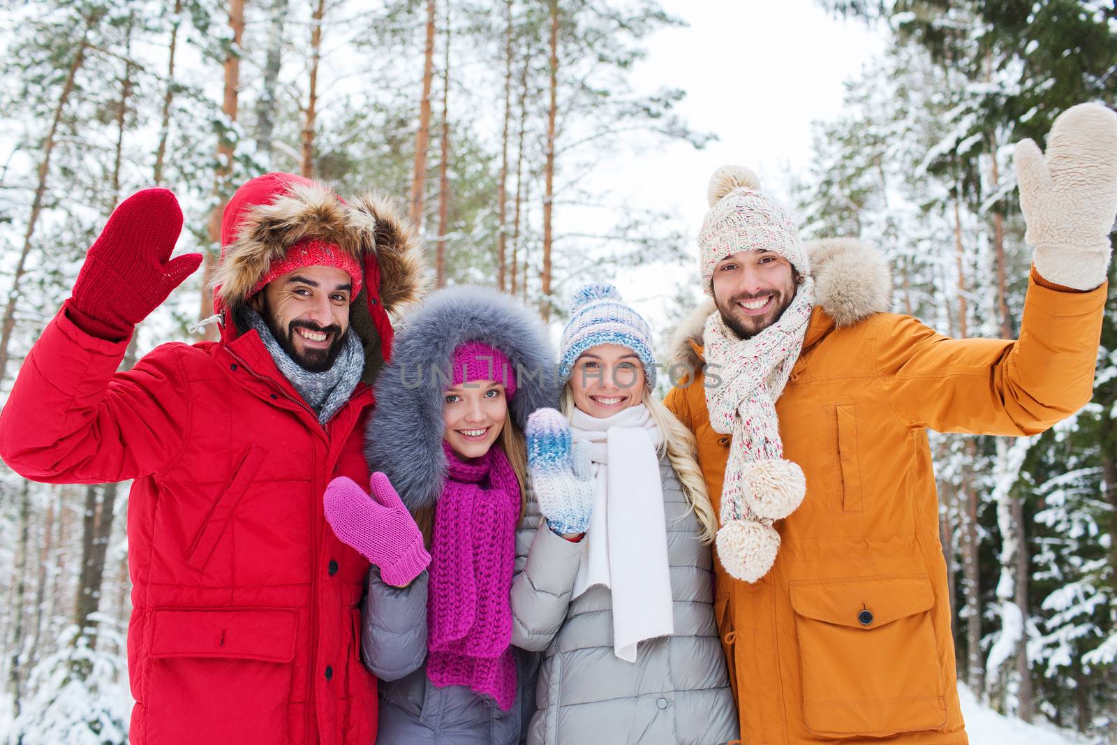 love, relationship, season, friendship and people concept - group of smiling men and women waving hands in winter forest