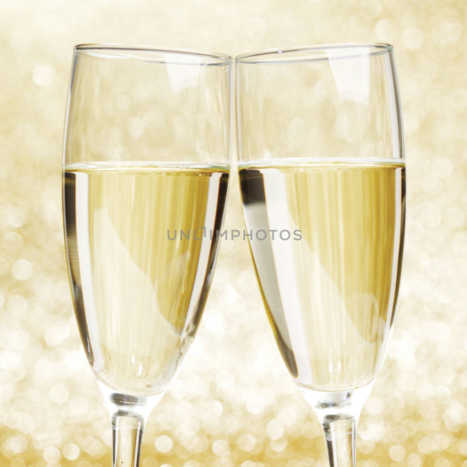 Flutes of champagne on golden holiday bokeh background