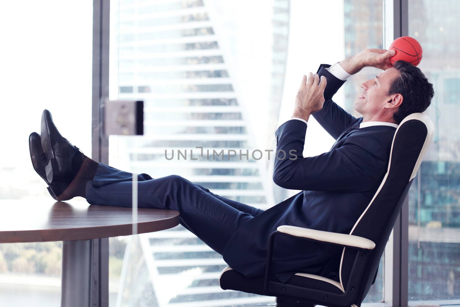 Business man playing with a basketball at the office