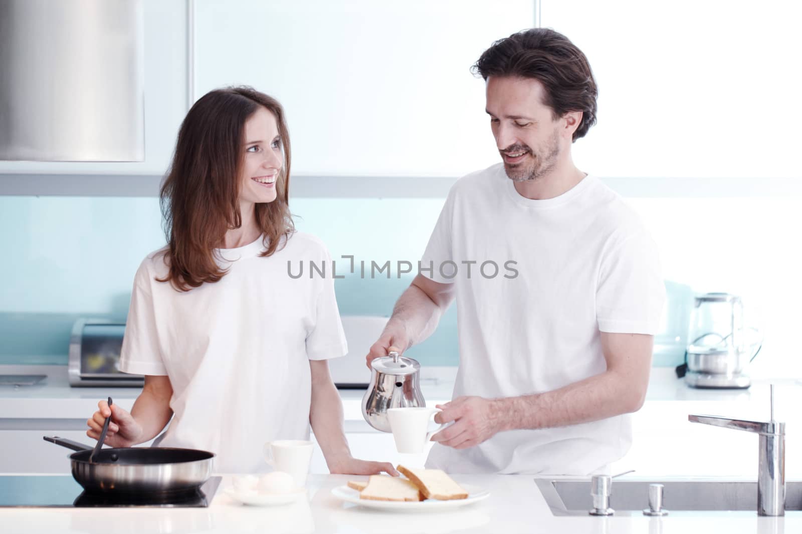 Happy couple cooking breakfast together in the kitchen