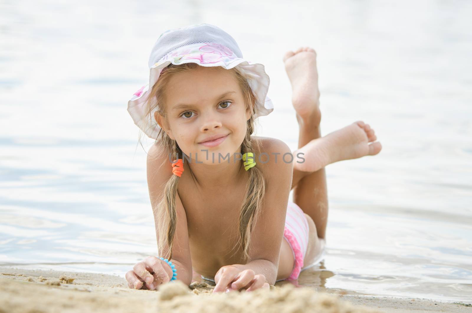 Six year old girl Europeans in panama lying on his stomach on the sand by the river