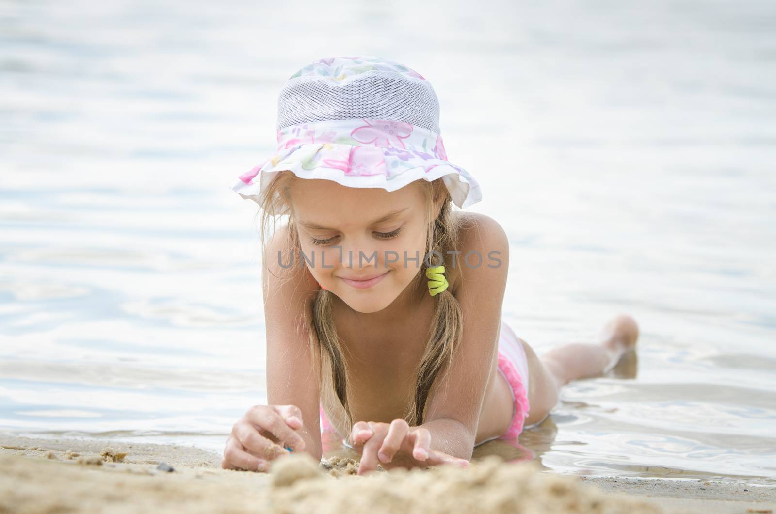 Six year old girl Europeans in panama lying on his stomach on the sand by the river