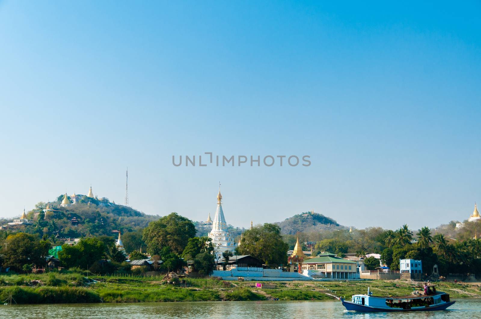Boat on Irrawaddy river with Pagoda and village close to Mandalay Burma Myanmar