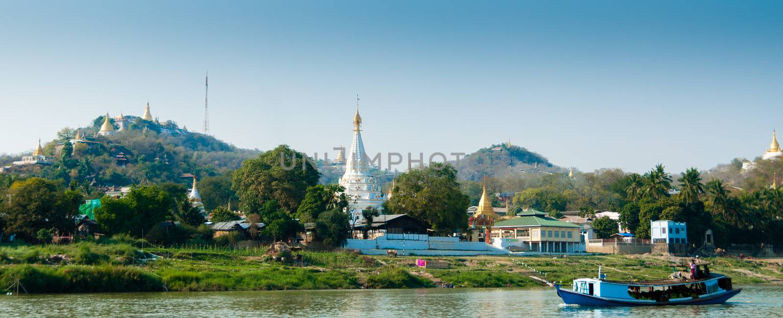 Boat on Irrawaddy river with Pagoda and village by attiarndt