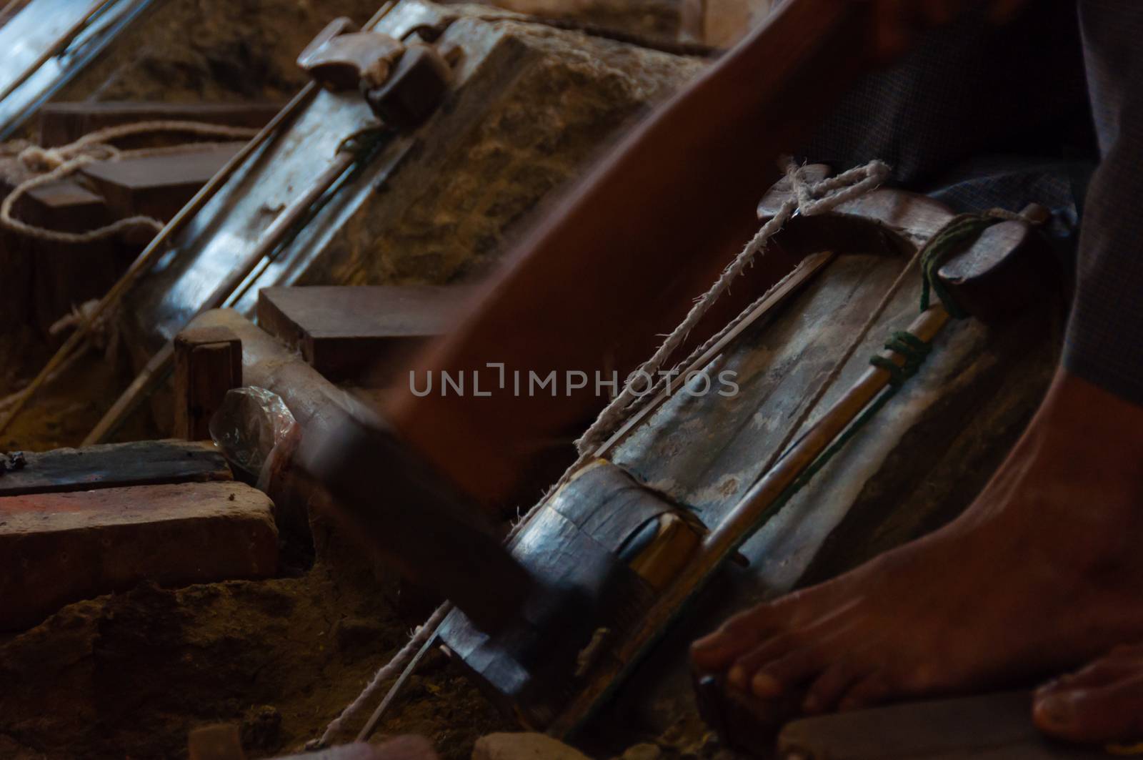 Young craftsman punching gold in the traditional way to make leaf gold. in Mandalay, Myanmar