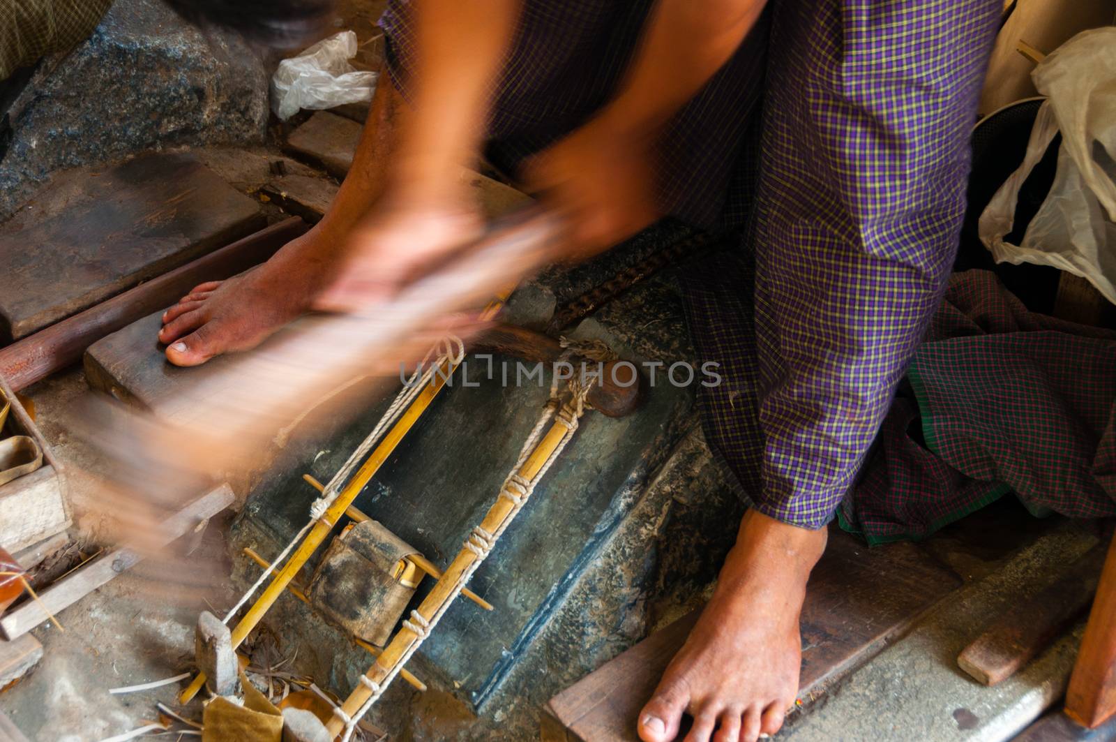 Young craftsman punching gold with a hammer by attiarndt