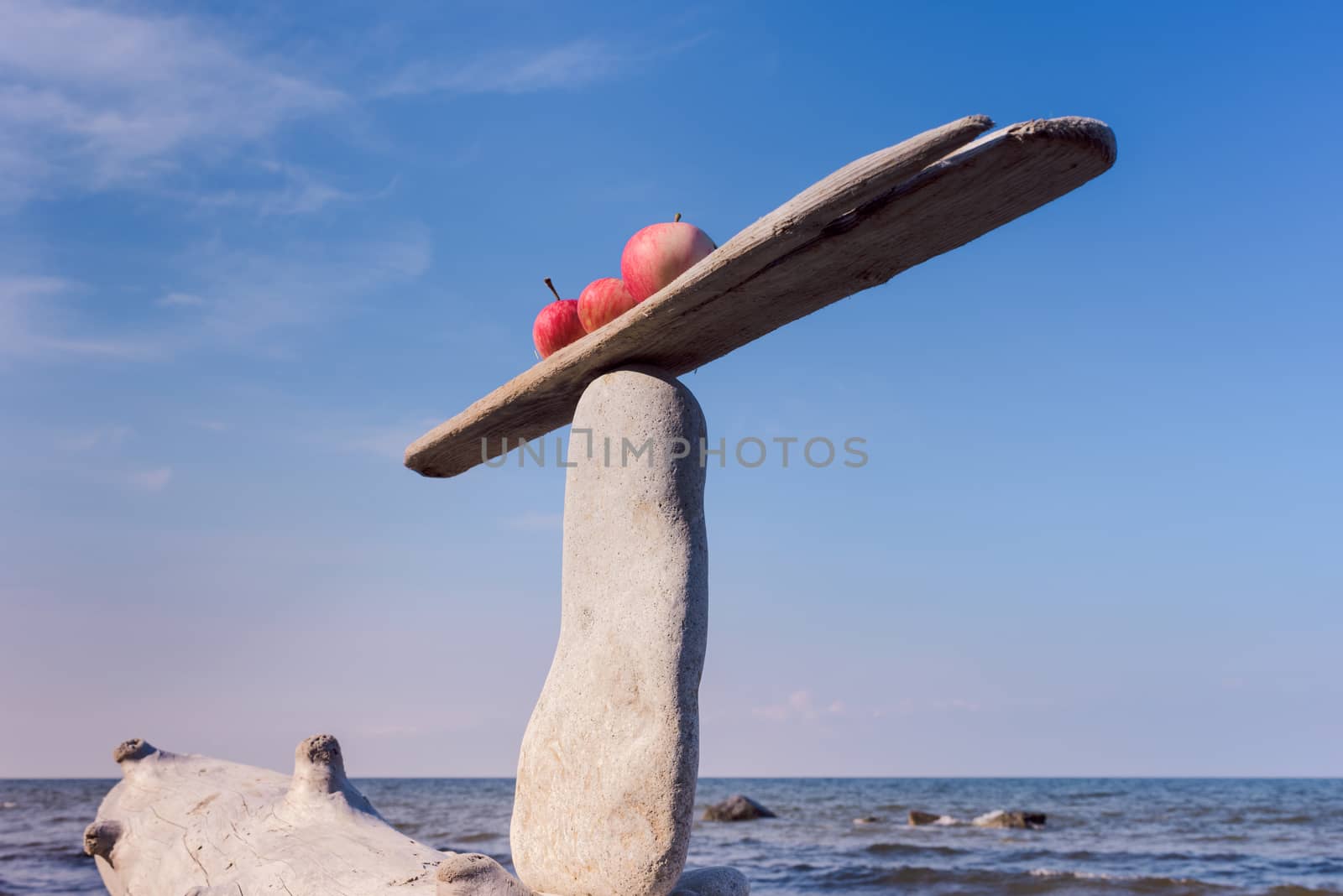 Three fresh apples in balance on narrow plank