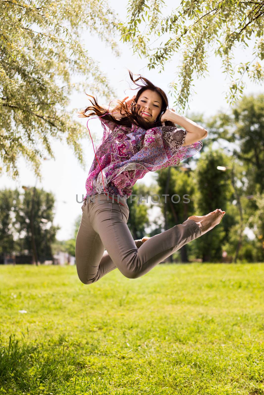 Happy Young Woman Jumping In The Park by MilanMarkovic78