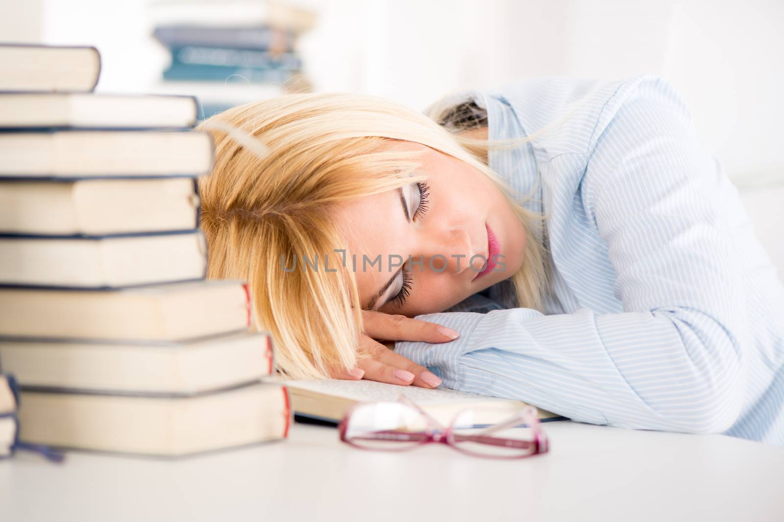 Tired student fell a sleep between many books, while learning.