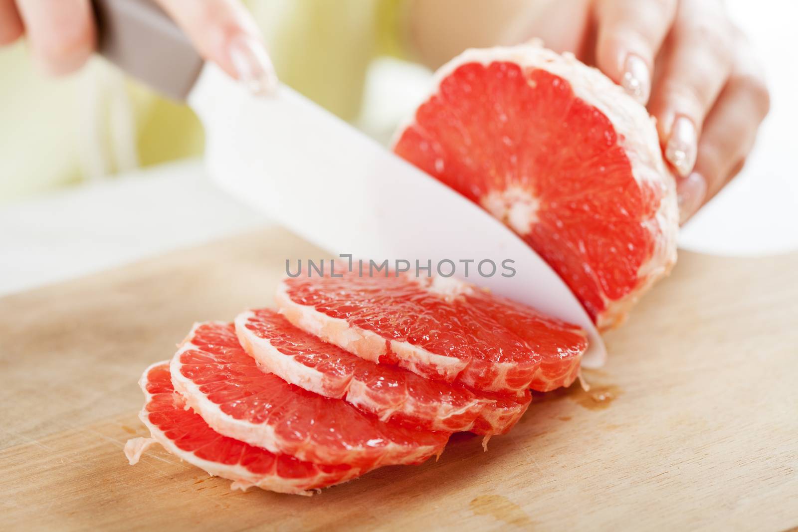 Female hands Cutting Grapefruit in the kitchen. Close-up. Selective Focus.