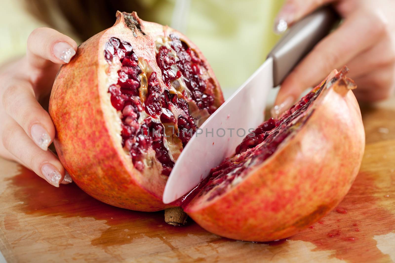 Female hands Cutting pomegranate in a kitchen. Close-up. Selective Focus.