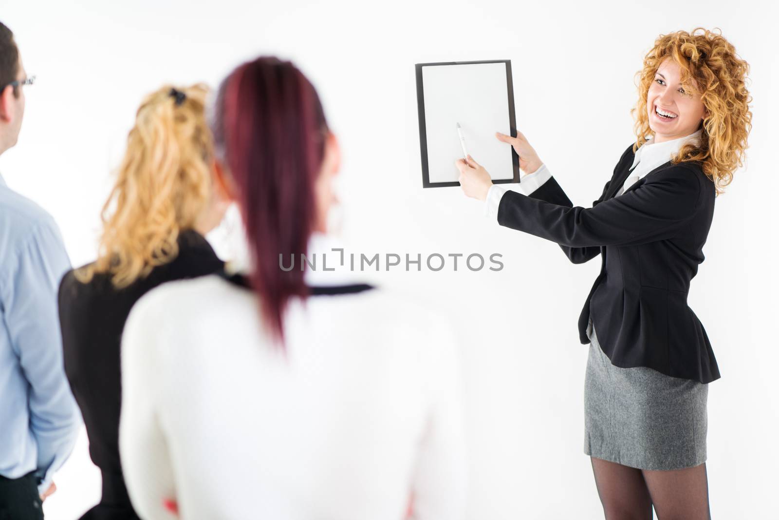 Friendly business woman explaining plan of work to her colleagues. The team is listening.