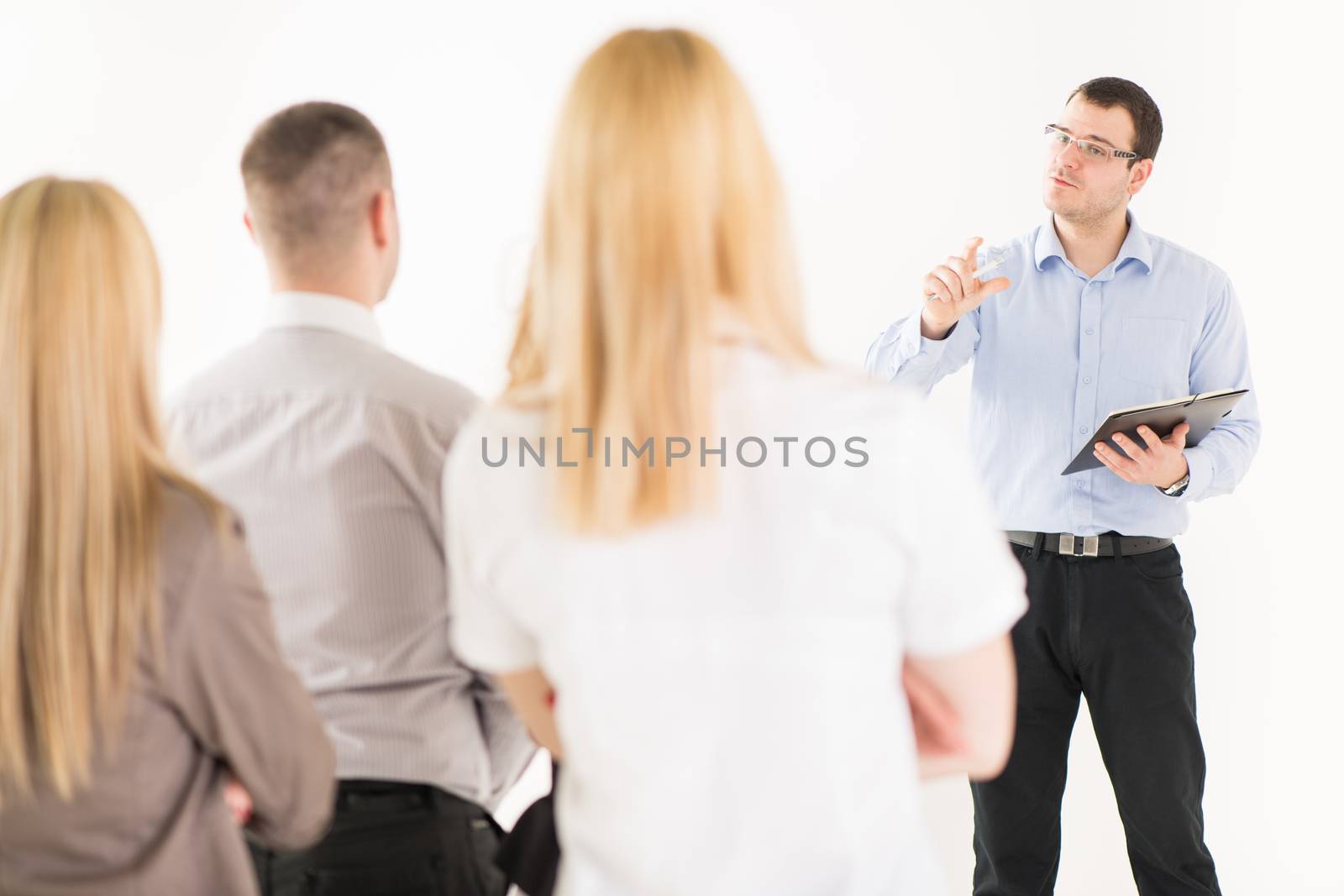 Friendly business man explaining plan of work in front of coworkers. The team is listening.