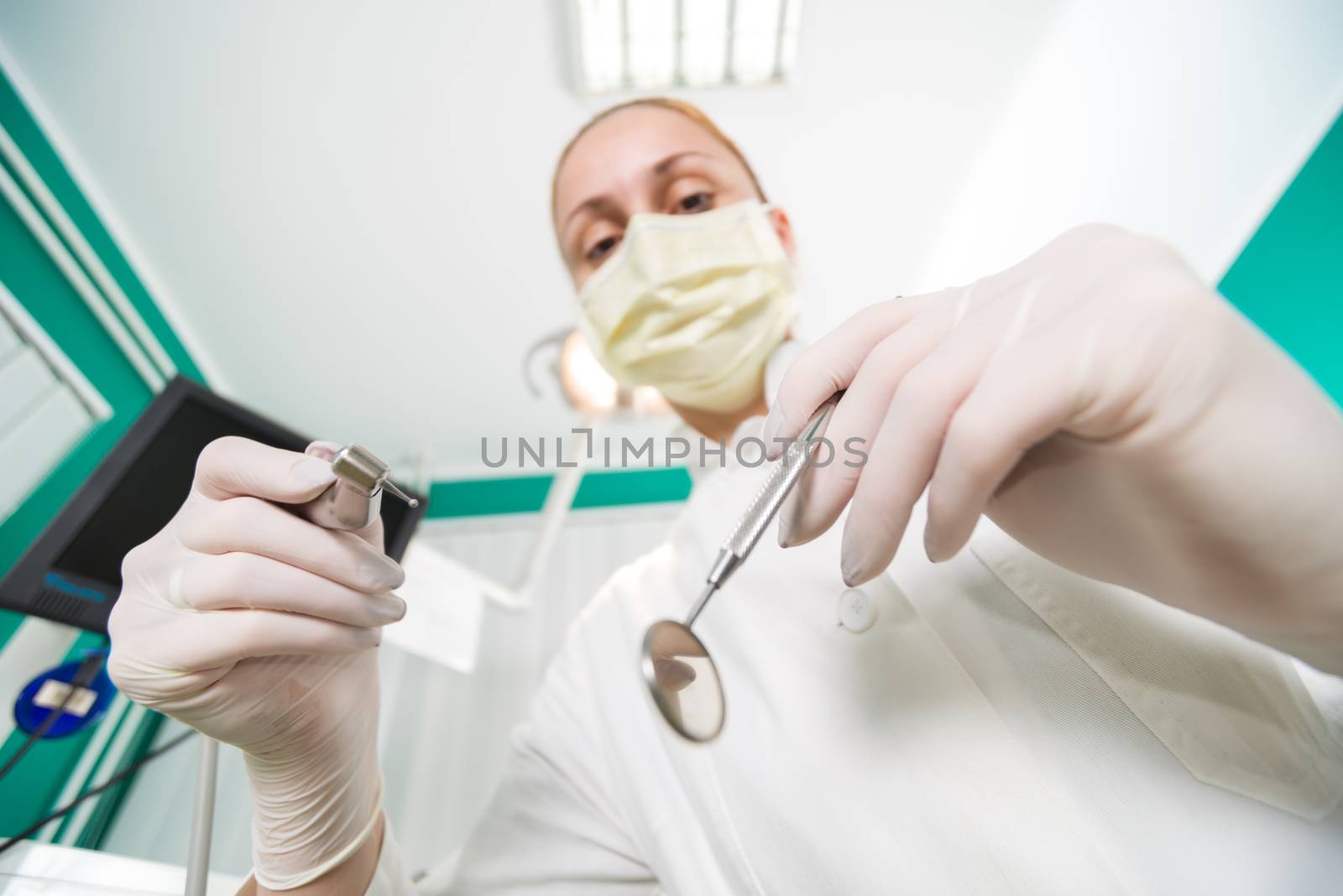 Dentist holding dental drill and Angled Mirror for inspecting a patient. Selective Focus.