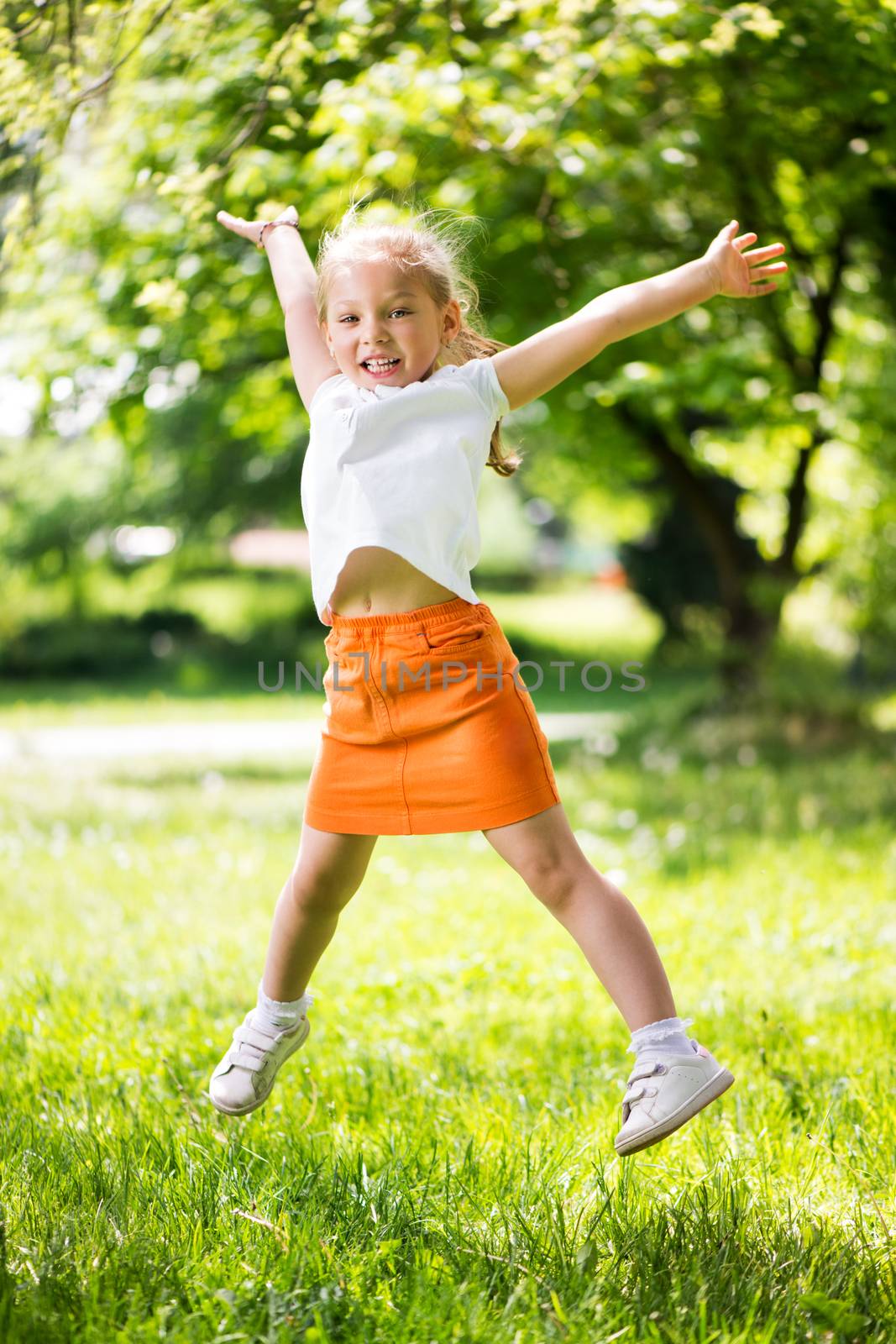 Cute Little Girl Jumping in The Park and having fun.