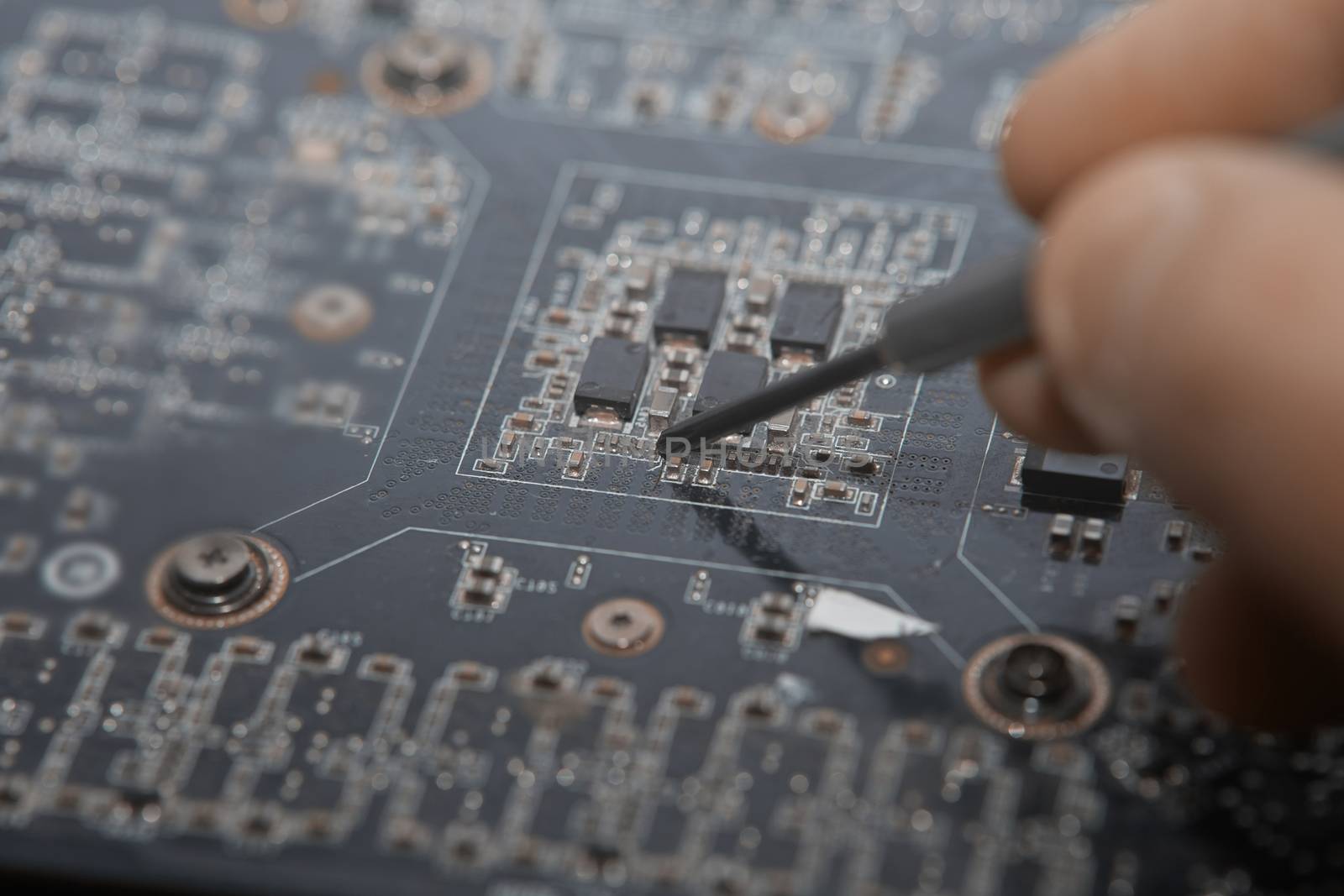 Human fingers making repair of motherboard. Close-up photo